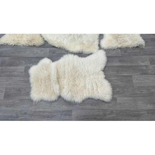 126 - Five items, one mid 20th century bamboo and rattan magazine rack and four sheepskin rugs, two Creati... 