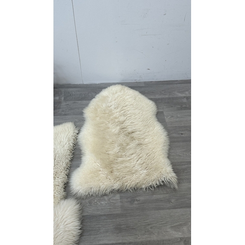 126 - Five items, one mid 20th century bamboo and rattan magazine rack and four sheepskin rugs, two Creati... 