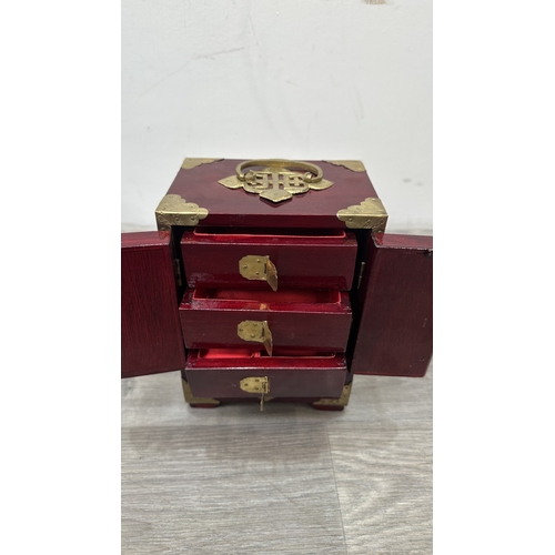 148 - Four items, one Chinese red lacquered wooden jewellery cabinet with brass decoration and carved cork... 