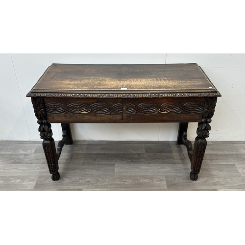 179 - A Victorian Gothic Revival carved oak two drawer hall/writing table - approx. 77cm high x 121cm wide... 