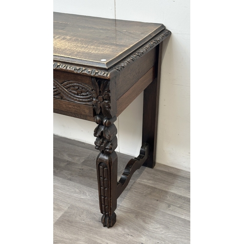 179 - A Victorian Gothic Revival carved oak two drawer hall/writing table - approx. 77cm high x 121cm wide... 