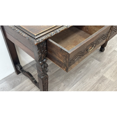 179 - A Victorian Gothic Revival carved oak two drawer hall/writing table - approx. 77cm high x 121cm wide... 
