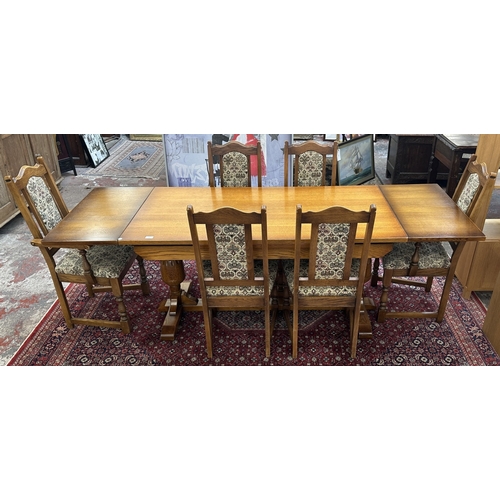 182 - A Wood Bros 'Old Charm' oak draw leaf dining table on carved baluster supports and six tapestry upho... 