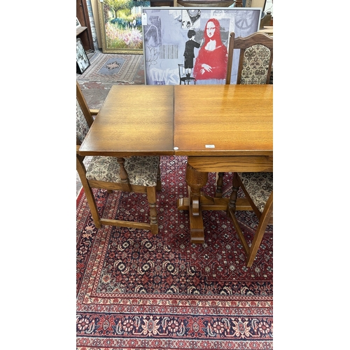 182 - A Wood Bros 'Old Charm' oak draw leaf dining table on carved baluster supports and six tapestry upho... 