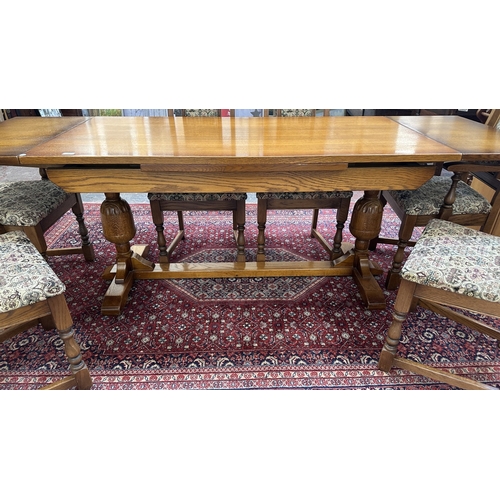 182 - A Wood Bros 'Old Charm' oak draw leaf dining table on carved baluster supports and six tapestry upho... 