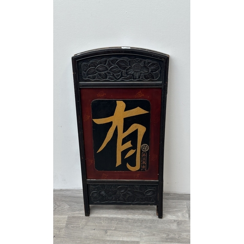 198 - A Chinese lacquered and carved wooden two section folding screen - approx. 91cm high x 86cm wide