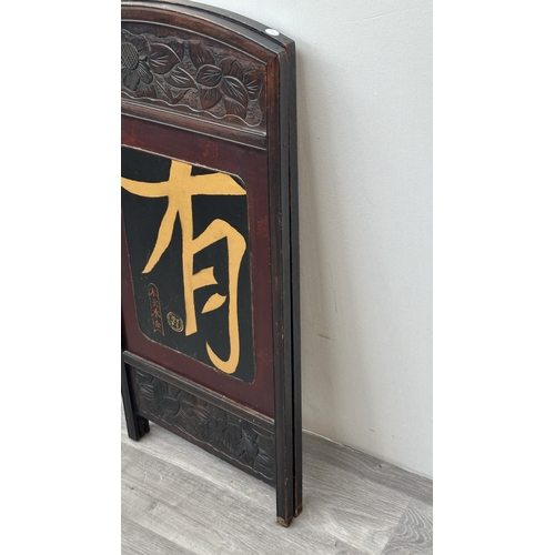 198 - A Chinese lacquered and carved wooden two section folding screen - approx. 91cm high x 86cm wide
