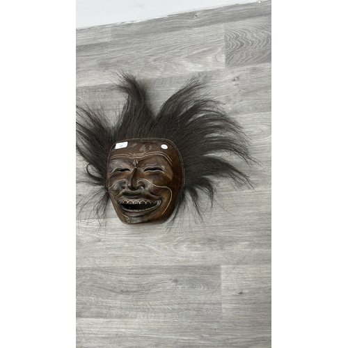 199 - A lacquered and carved wooden tribal mask with hair - approx. 46cm high x 57cm wide including hair