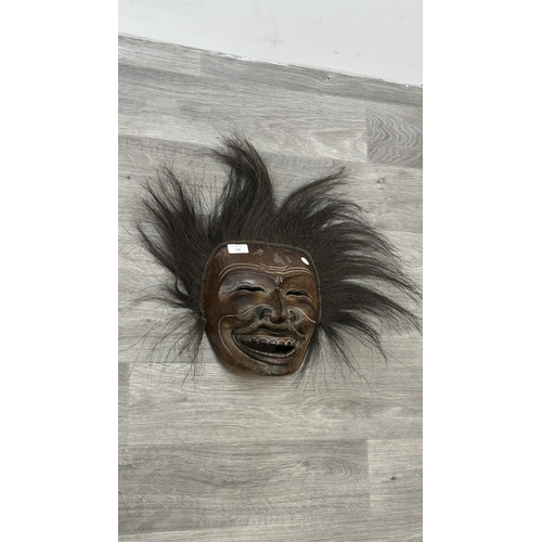 199 - A lacquered and carved wooden tribal mask with hair - approx. 46cm high x 57cm wide including hair
