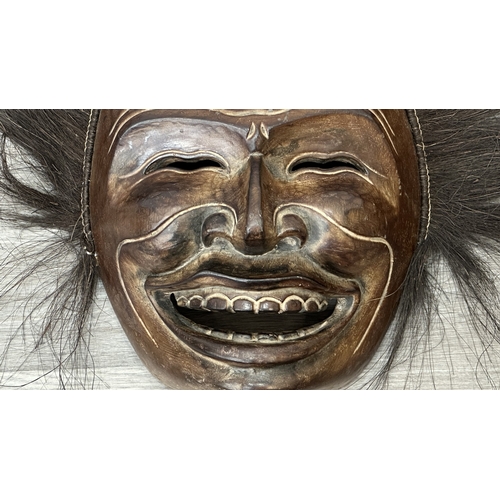 199 - A lacquered and carved wooden tribal mask with hair - approx. 46cm high x 57cm wide including hair