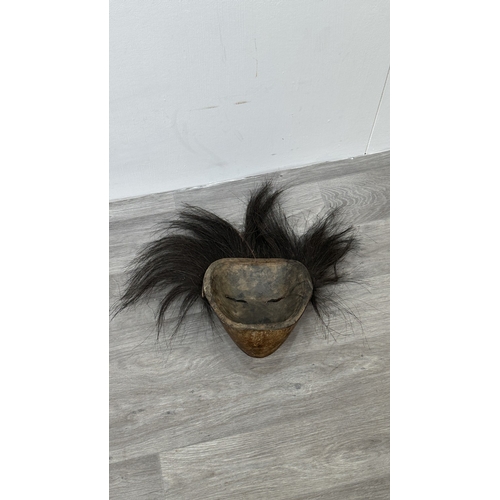 199 - A lacquered and carved wooden tribal mask with hair - approx. 46cm high x 57cm wide including hair