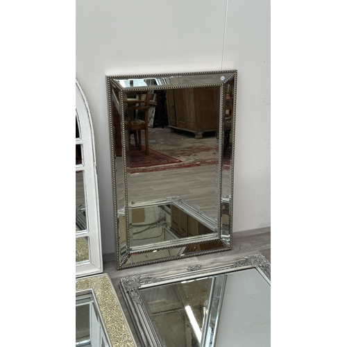 255 - Four modern framed wall mirrors, one white painted arched, one silver painted and bevelled, one Fren... 