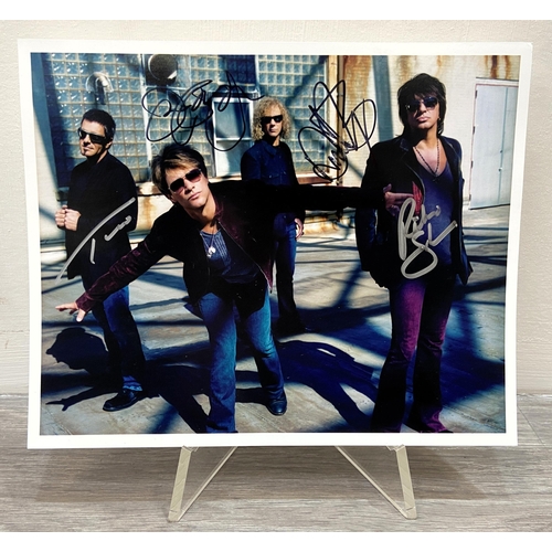 114 - A signed colour photograph of Bon Jovi features hand-signed autographs from band members Jon Bon Jov... 