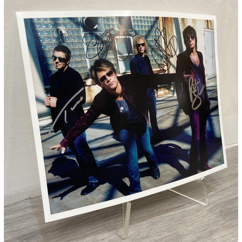 114 - A signed colour photograph of Bon Jovi features hand-signed autographs from band members Jon Bon Jov... 