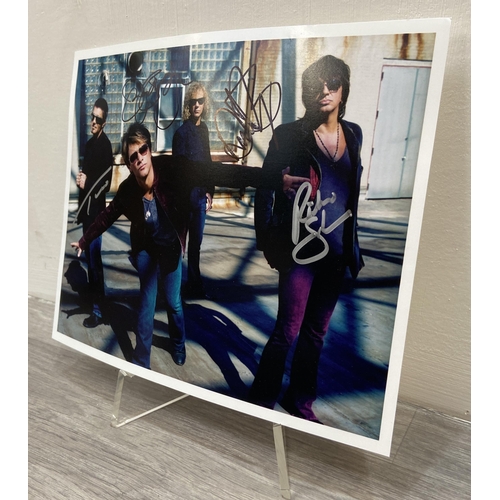 114 - A signed colour photograph of Bon Jovi features hand-signed autographs from band members Jon Bon Jov... 