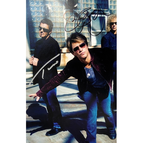 114 - A signed colour photograph of Bon Jovi features hand-signed autographs from band members Jon Bon Jov... 