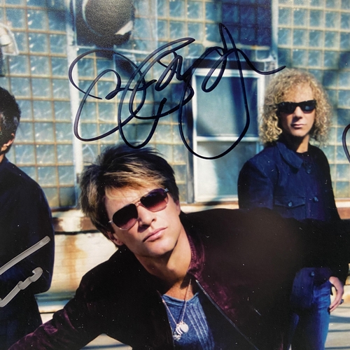 114 - A signed colour photograph of Bon Jovi features hand-signed autographs from band members Jon Bon Jov... 