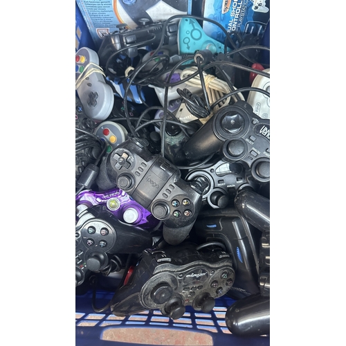 A box containing a large collection of assorted games controllers