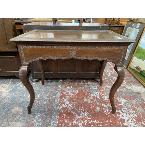 246 - A late 19th/early 20th century carved mahogany writing table with foliate design and cabriole suppor... 