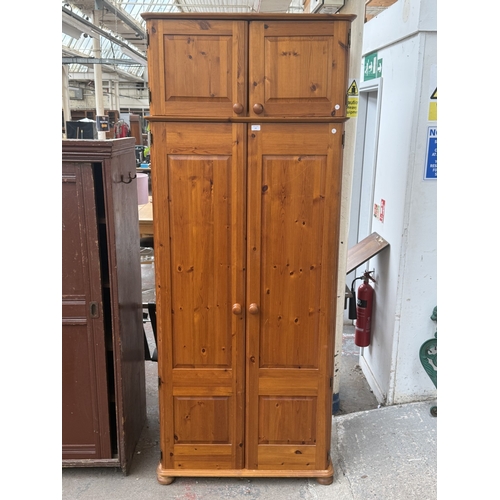 107 - A pine double wardrobe with upper storage compartment - approx. 221cm high x 90cm wide x 60cm deep