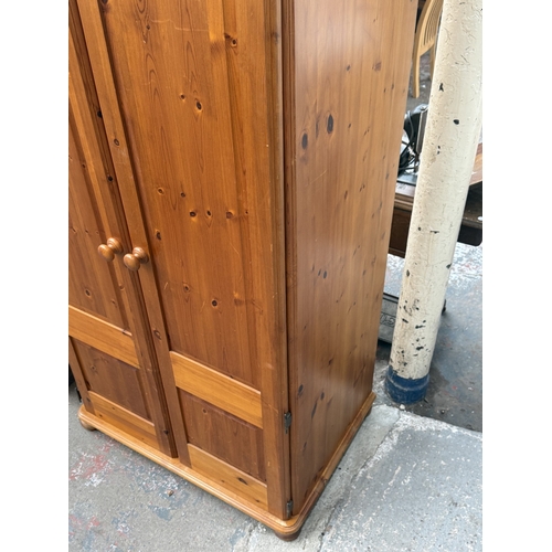 107 - A pine double wardrobe with upper storage compartment - approx. 221cm high x 90cm wide x 60cm deep