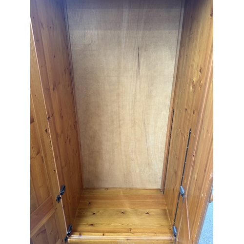 107 - A pine double wardrobe with upper storage compartment - approx. 221cm high x 90cm wide x 60cm deep
