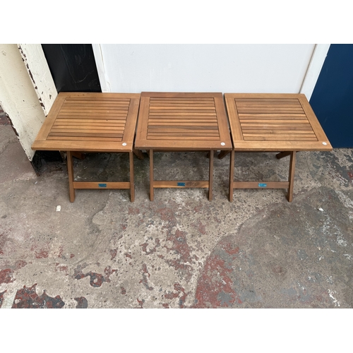 140 - Four stained teak folding garden side tables, three approx. 45cm high x 45cm square and one with rem... 