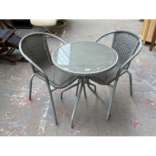 160 - A grey metal three-piece patio set comprising circular glass-top table and two plastic wicker effect... 