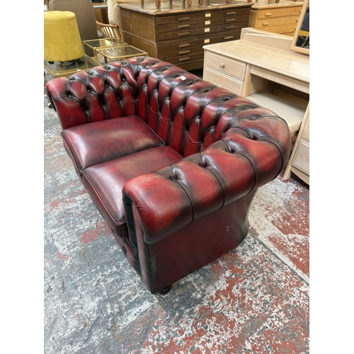 173 - An oxblood leather Chesterfield two-seater sofa - approx. 76cm high x 140cm wide x 75cm deep