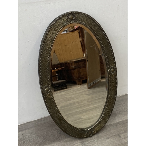 283 - An arts and crafts style embossed brass framed oval bevelled edge wall mirror - approx. 70cm high x ... 