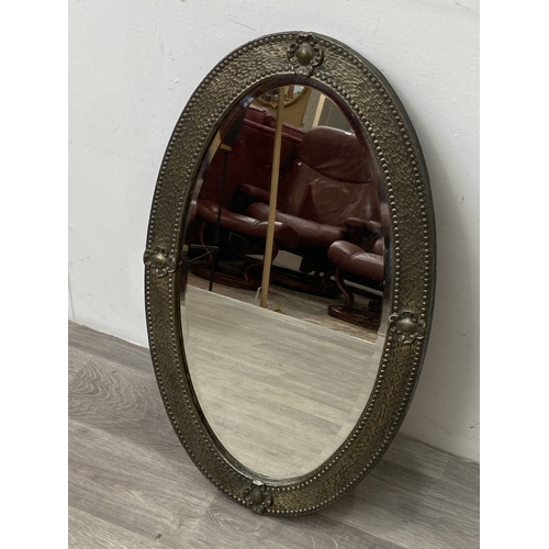 283 - An arts and crafts style embossed brass framed oval bevelled edge wall mirror - approx. 70cm high x ... 