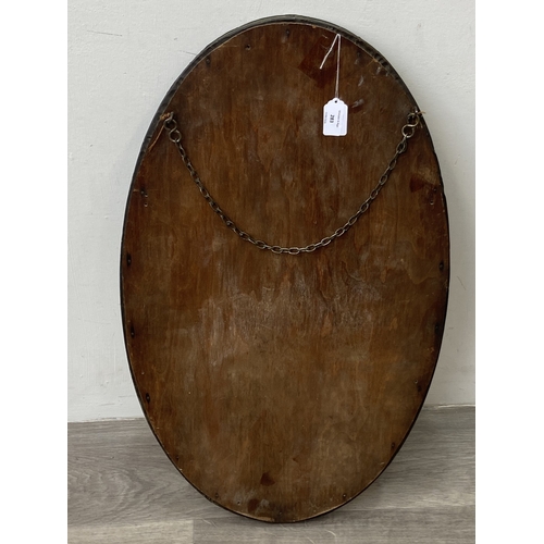 283 - An arts and crafts style embossed brass framed oval bevelled edge wall mirror - approx. 70cm high x ... 