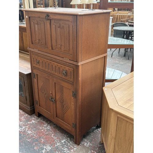 96 - A Jaycee carved oak linenfold cocktail cabinet - approx. 124cm high x 75cm wide x 43cm deep