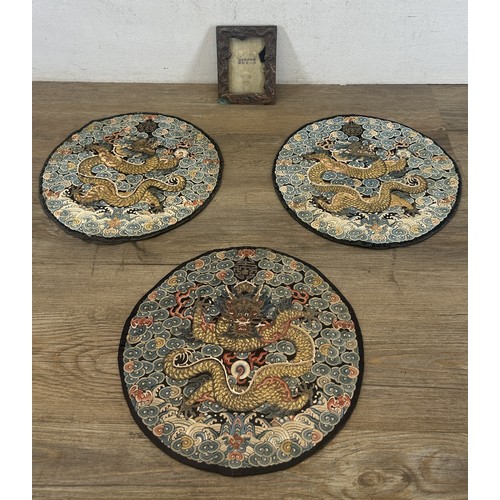 Four Oriental items, three antique Chinese Qing dynasty embroidered silk five-claw dragon roundels and one copper picture frame
