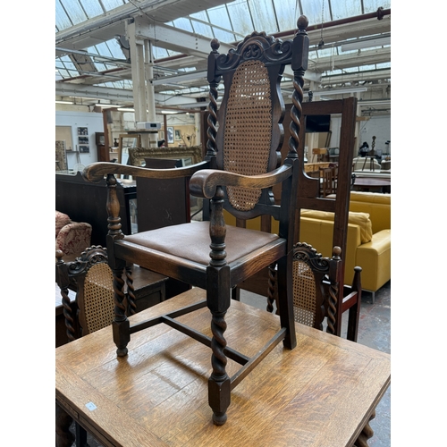 12 - An early 20th century oak draw leaf barley twist dining table and four oak and cane back barley twis... 