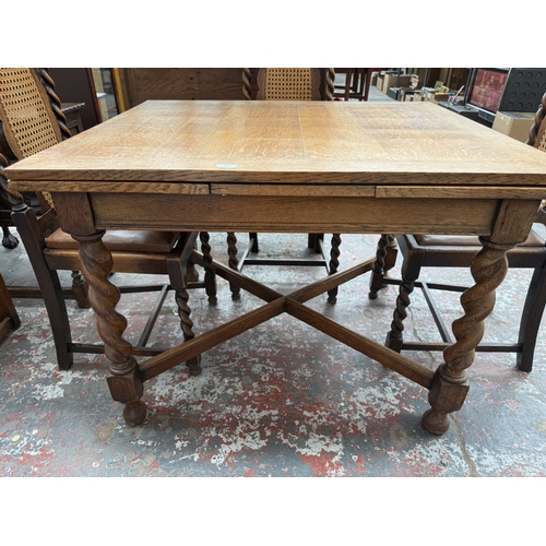 12 - An early 20th century oak draw leaf barley twist dining table and four oak and cane back barley twis... 