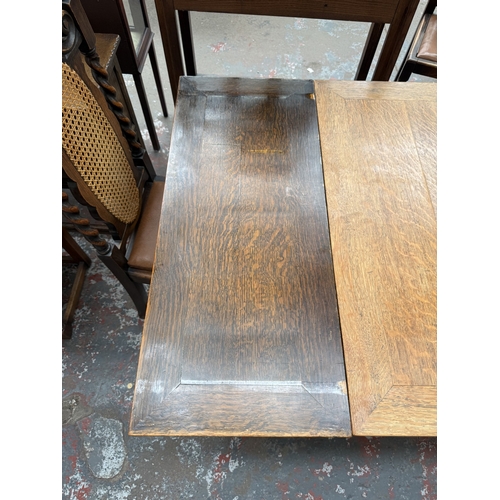 12 - An early 20th century oak draw leaf barley twist dining table and four oak and cane back barley twis... 