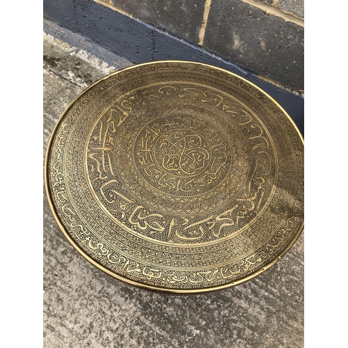 61 - An islamic style brass tray top ocassional base, together with a copper wall hanging plaque 60cm dia... 