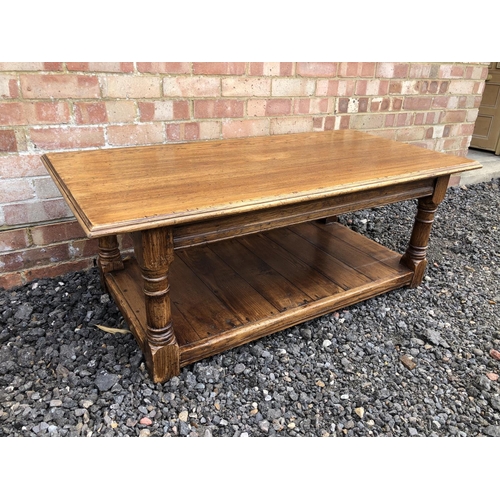 51 - A reproduction oak coffee table with a solid top and panelled lower shelf 121x60x45