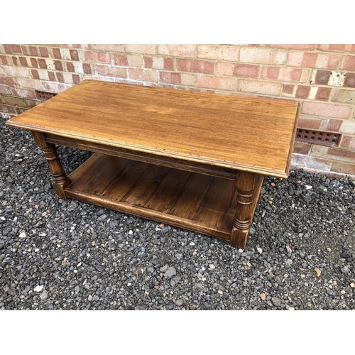 51 - A reproduction oak coffee table with a solid top and panelled lower shelf 121x60x45