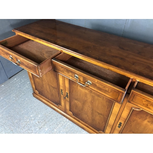 204 - A reproduction yew wood sideboard, three drawers over three cupboards 153x40x87