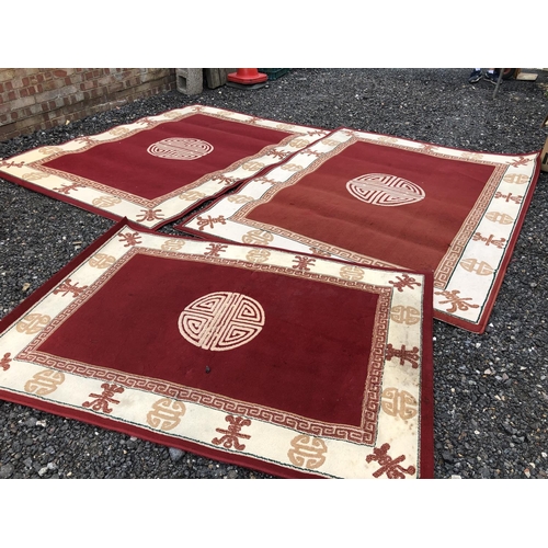 33 - A pair of large red Chinese rugs together with a matching small rug