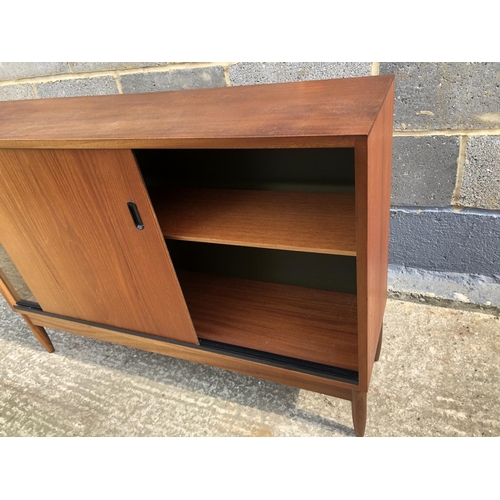 133 - A 1970's teak bookcase with sliding doors 105x28x74