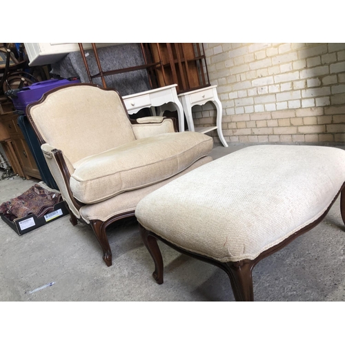 161 - A large cream upholstered beige French style armchair with footstool