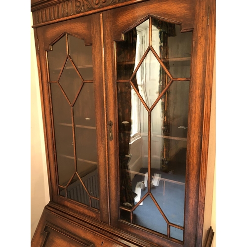 242 - An early 20th century oak bureau bookcase, a glazed cabinet top with three adjustable shelves over a... 