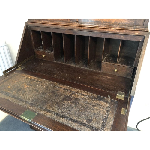 242 - An early 20th century oak bureau bookcase, a glazed cabinet top with three adjustable shelves over a... 