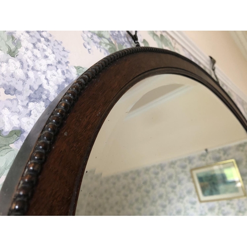 254 - An oval oak framed mirror with bevelled glass