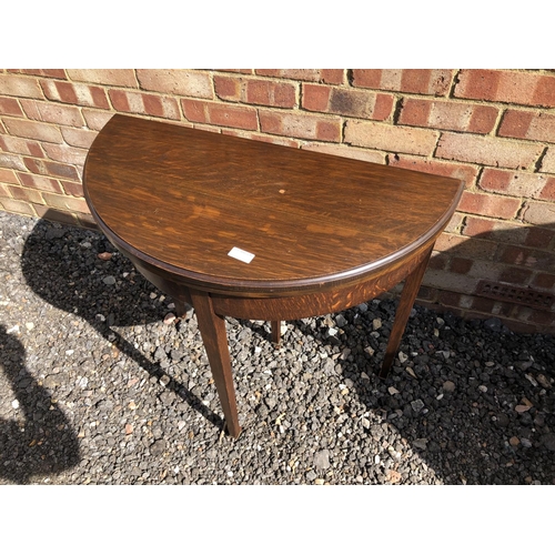 368 - A Demi lune oak fold over card table, with a telescopic leg sliding to support the green baize playi... 