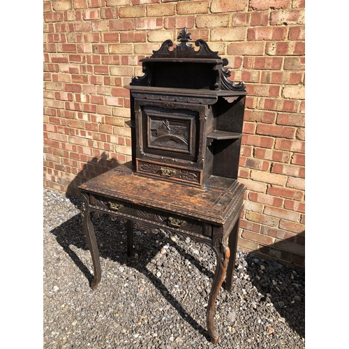 371 - A carved oak writing desk with a fall front to reveal pigeon holes and a leather writing surface