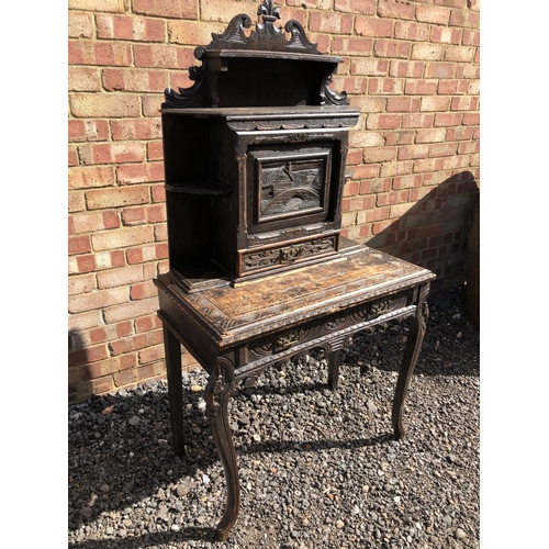 371 - A carved oak writing desk with a fall front to reveal pigeon holes and a leather writing surface